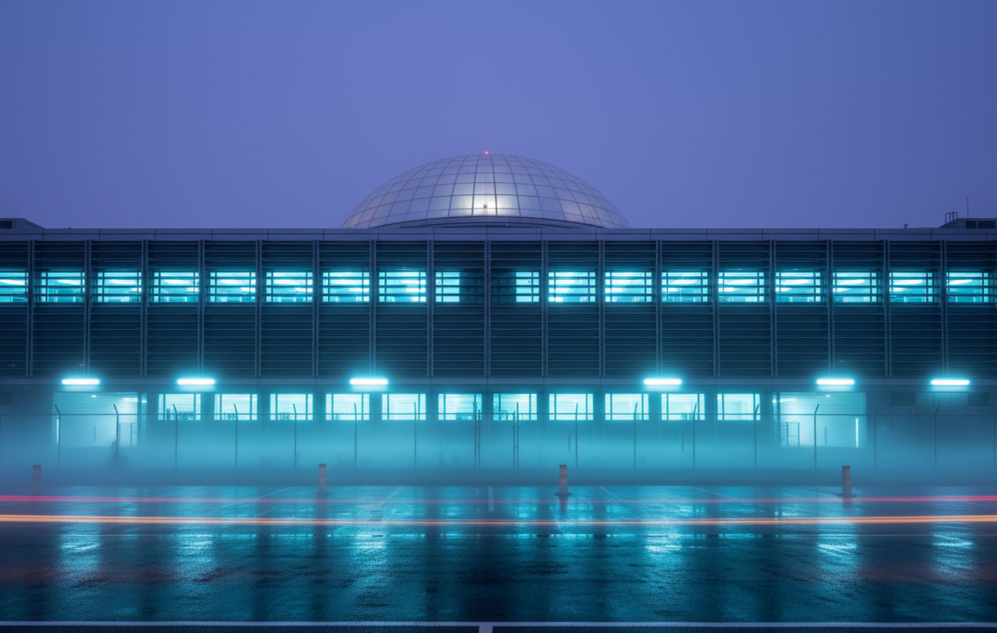 Hyperscale data centre at dusk with blue lighting and wet-ground reflections