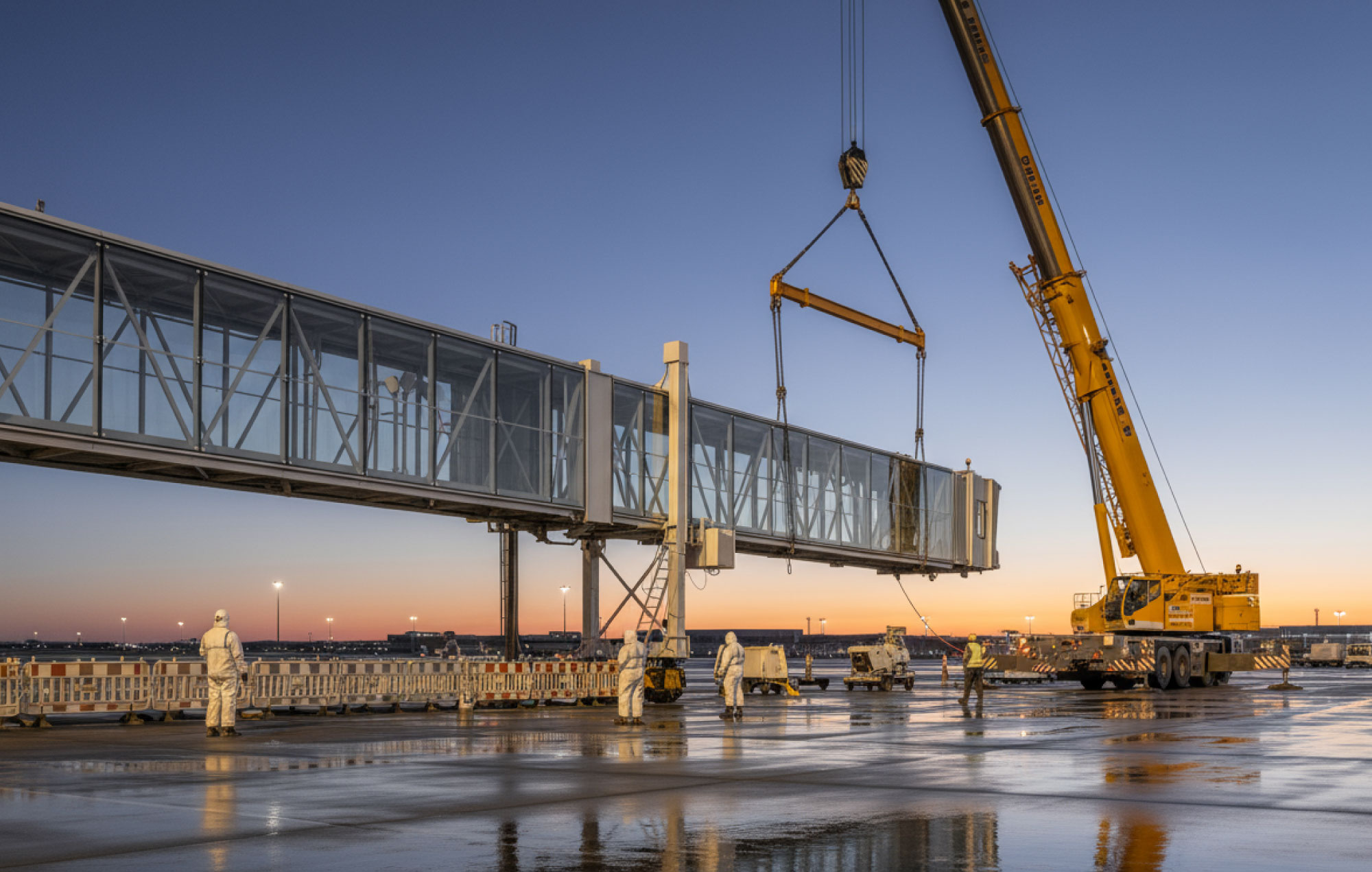 Large logistics hub at dusk with loading bays, canopy lighting and wet-ground reflections