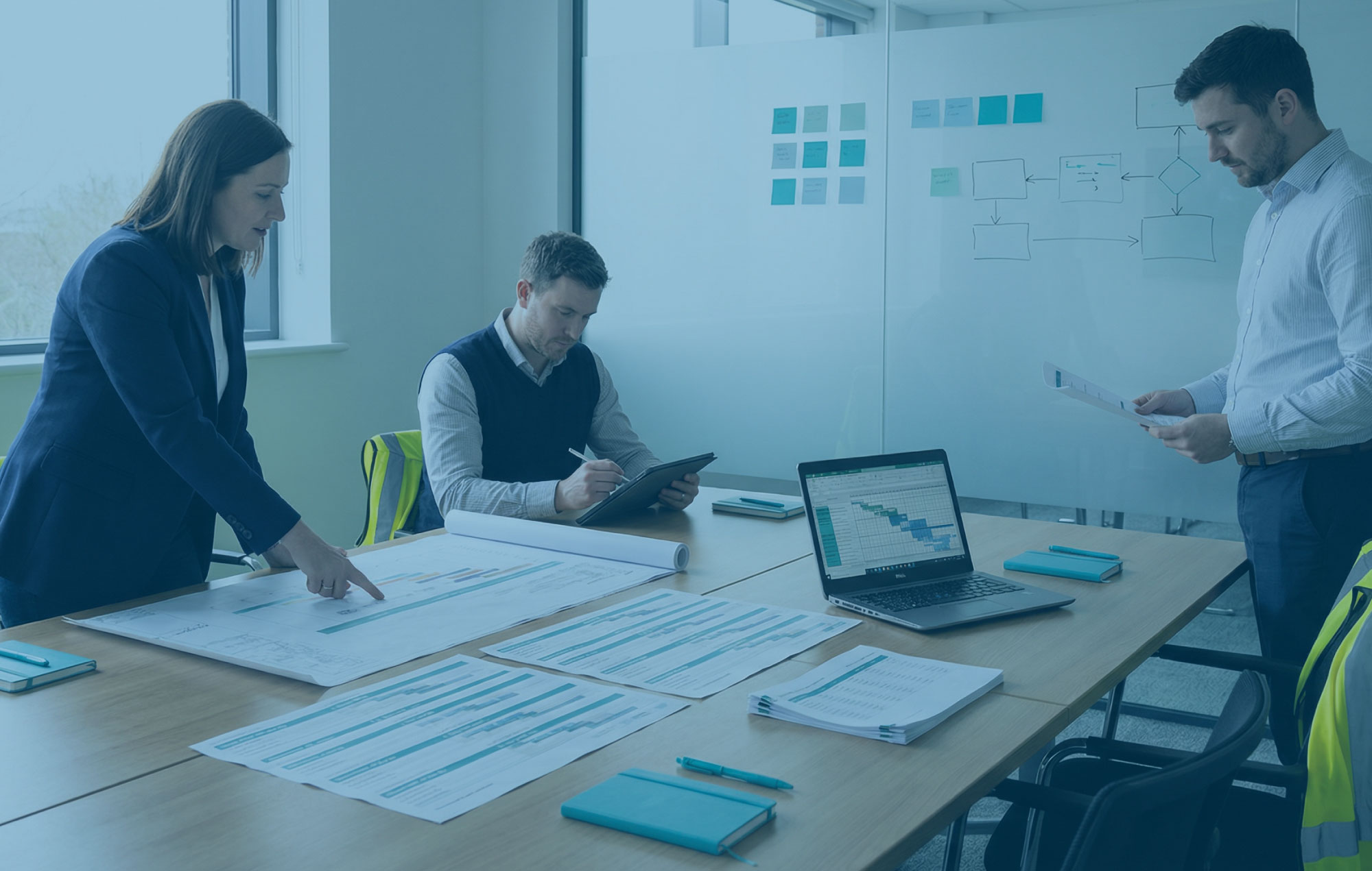 MEP preconstruction workshop with plans, cost models and framework options on a table in soft daylight