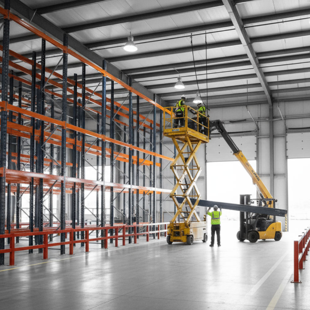 City-centre mixed-use regeneration at blue hour with façade retention steelwork, tower crane, tidy hoardings and public realm diversions